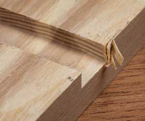 Blowout occurs as the bit emerges from the wood at cut's end. A scrap clamped to the work's edge prevents damage to it; instead the blowout affects the scrap.