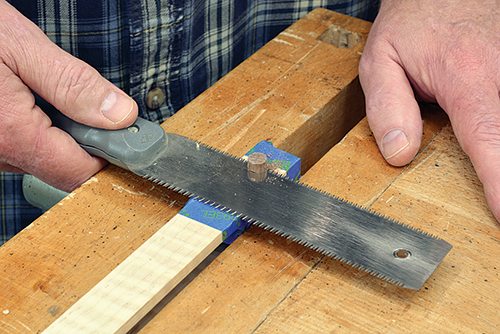 Trim the accent dowel with a flush-cut saw. Masking tape helps protect the workpiece from wayward scratches.