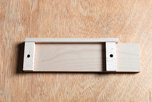 The author used this drilling jig to register his train car bases for boring hitch pin holes. The hole size on one end will fit the pins tightly for gluing, while the hole on the other end is slightly larger so the pin on a mating car can swivel.