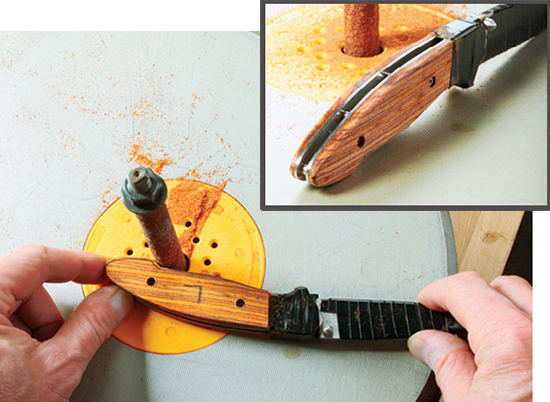 Screw the wooden scales in place, then sand them down with a coarse drum or sleeve until their edges are flush with the knife’s liners.