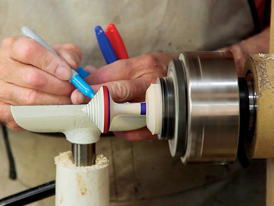 Photo 3: As the lathe spins, decorate the top’s surfaces with colored bands using felt-tip markers.