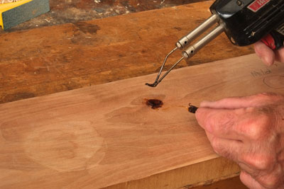 The traditional way to apply shellac to a blemish is to heat a pallet knife with a shellac flake on it with an alcohol lamp. Once the shellac melts, simply trowel it into the defect. I found that it is possible to order a special tip for my Weller Soldering iron that works even better than a pallet knife. Intended for smoothing solder it is Weller part #6160. Here I am using it to burn shellac into a blemish. Shellac is a thermal plastic, viscous when heated and hard once dry, which only takes a couple of minutes. Build shellac higher than the surrounding wood and sand smooth once filled. You can also sprinkle some ground color into the shellac while it is still hot.