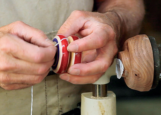 Mount yo-yo string to the axle by untwisting the doubled end, slipping it over the axle and re-twisting. Adding a second loop can help increase the friction.