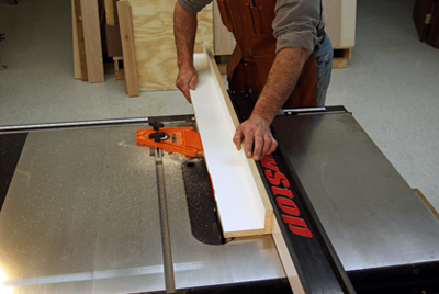 Plug the saw in and cut into the edge of the shop-made fence. A feather board helps keep the work tight to the rip fence. 