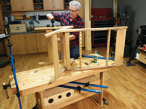 Resting chair frame on workbench to install screws