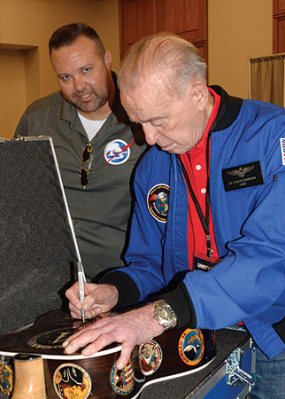 Astronaut Walt Cunningham signing guitar
