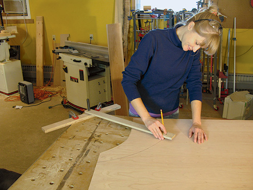 Marking out arcs on plywood panel for desk