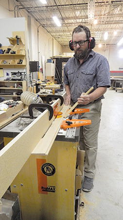 In two of the lap-siding pieces, rout a narrow groove along the thin, top edge. The author clamped an overly long fence to his router table fence to add bearing support for this operation.