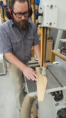 Lay out the two roof end pieces to create its pitch, then cut these angles at the band saw, freehand. A tapering jig would also work.