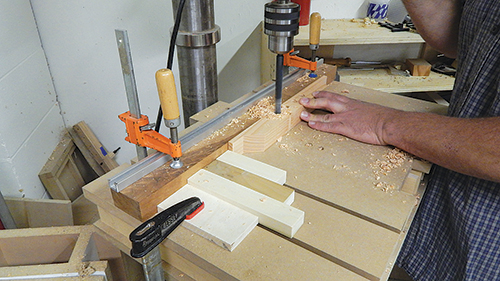 A stop block clamped to the drill press table, and three spacers, make it easy to drill the top bars’ three through holes so they’re evenly spaced.