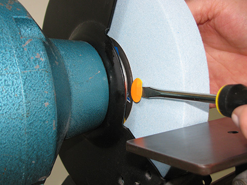 Inserting small sticker shim on grinding wheel