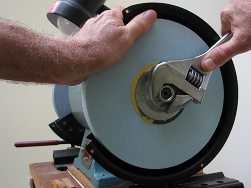 Attaching bench grinder wheel with a wrench and hand