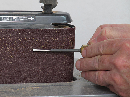 Grinding the edge of birdcage awl on a sander