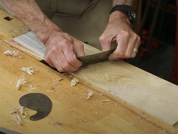 Smoothing a board with a cabinet scraper