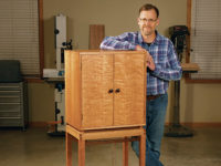 Chris Marshall standing with a cherry wine cabinet with walnut accents