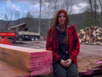 Emerald Breon sitting with freshly cut cherry lumber