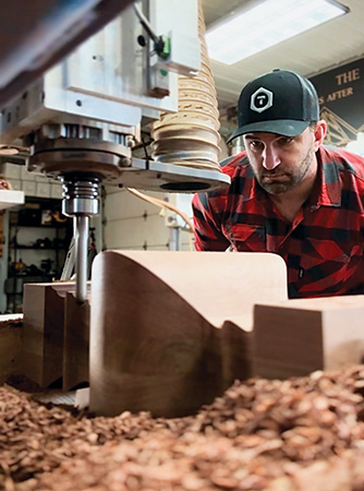 Dan Wellens observing a CNC machine cutting a table leg