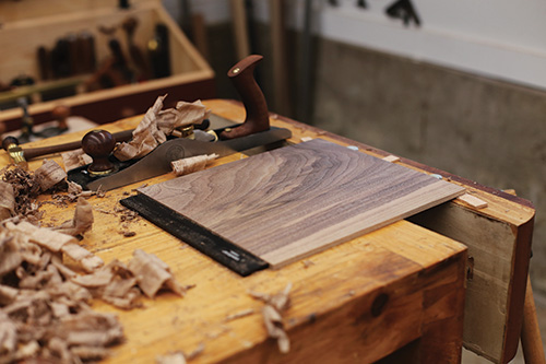 Smoothing dovetailed whiskey cabinet door panel with hand plane