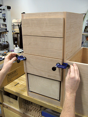Using drawer front installation clamps to hold drawer faces in place