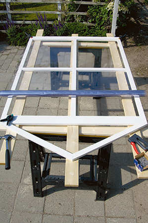 Painted fold-up greenhouse panel with plastic sheet stapled across it