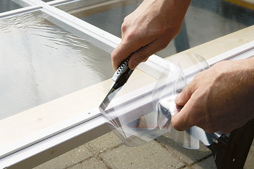 Trimming polyethylene sheet with razor for fold-up greenhouse