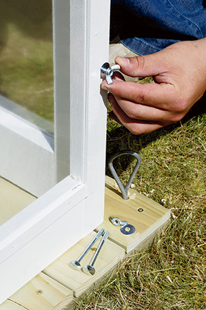 Screwing in wingnuts to secure sides on fold-up greenhouse frame