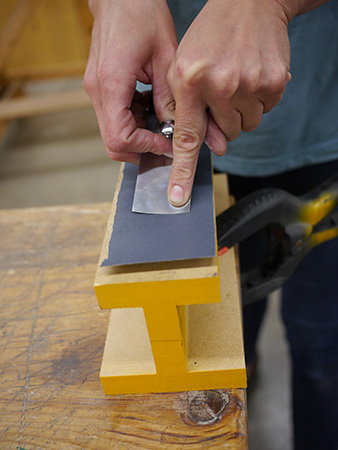 Sweeping plane blade across sandpaper