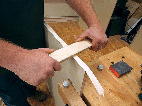 Using scrap lumber to press down veneer tape