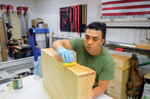 Huy Huynh wiping a finish on a drawer