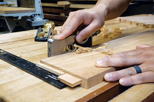 Huy Huynh smoothing panel edges with hand plane