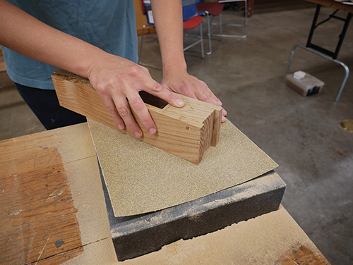 Sanding down wooden hand plane body on hard surface