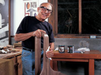 Sam Maloof posing with cans of his finishing product