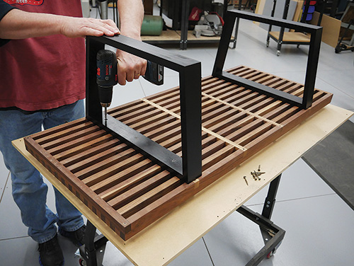 Screwing created legs into modern coffee table base and slats