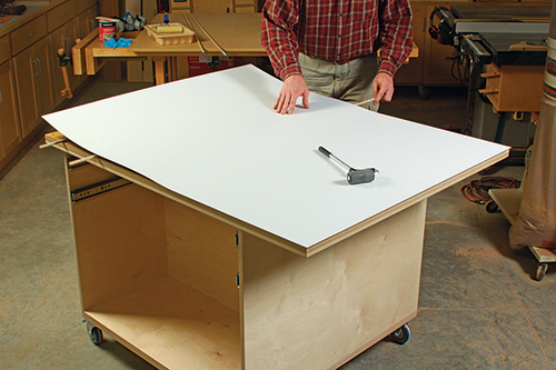 Plastic countertop laminate (right) forms a slick, durable work surface. Long dowels help position it over the substrate, once contact cement is rolled on and becomes tacky.