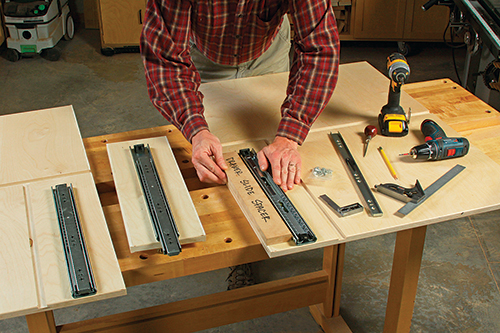 The author used a spacer made from scrap to help center the drawer slides on the carcass sides and drawer divider before attaching them. This hardware is easiest to install now, rather than into deep drawer pockets later.