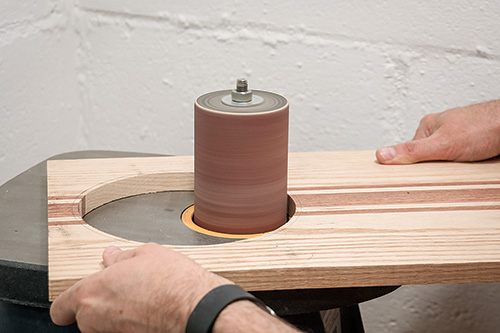 Sanding down cutting board strainer hole with a spindle sander