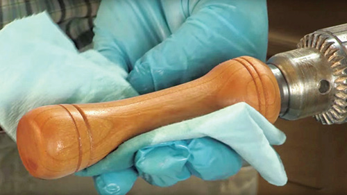Applying shellac to a pizza cutter handle on a lathe
