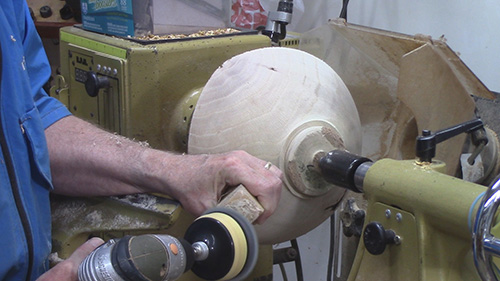 Refreshing sanding disc by running it on a cleaning stick