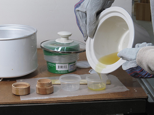 Pouring beeswax and mineral oil mixture into plastic container