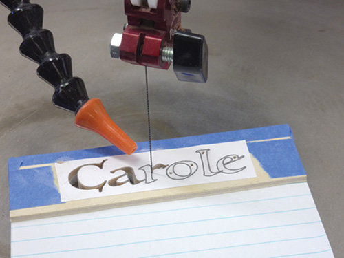 Notepad taped to wood and cut on a scroll saw