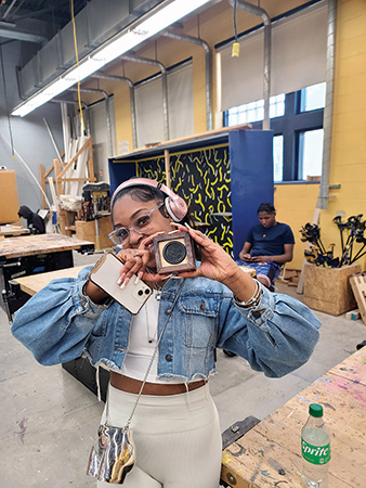 Student holding up her Bluetooth speaker