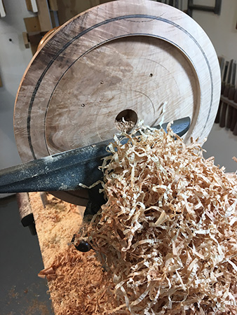 Wood shavings and progressive cuts in bowl blank