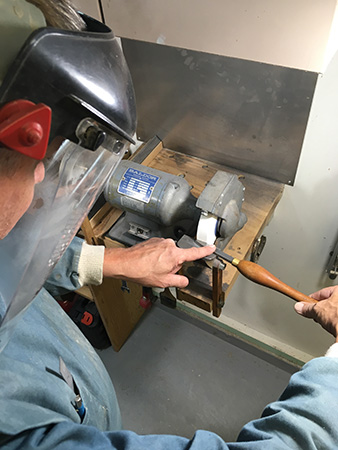 Adjusting scraper on sharpening stone