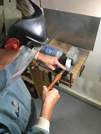 Using finger to press blade edge on grinder