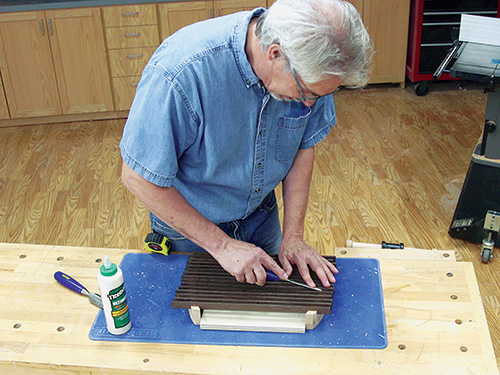 Scraping excess glue off trivet slat with chisel