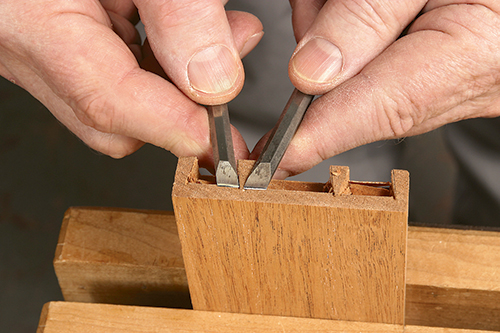 Using two skew chisels to smooth out end of dovetail joint