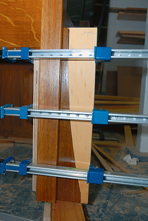 A custom clamping block (offcuts will work) simplifies gluing the curved corbels to the settle legs.