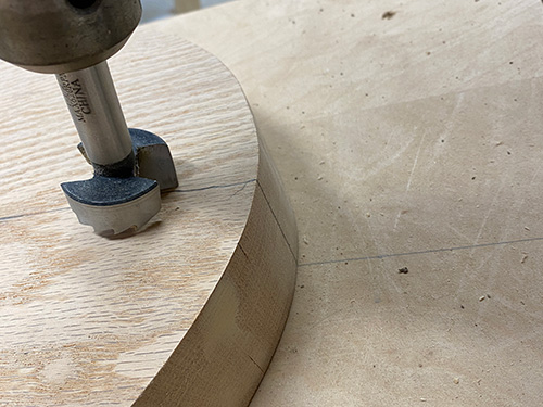 Placing stool seat blank on drilling jig