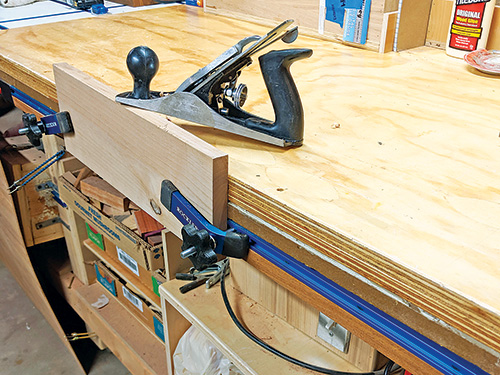 Board clamped to t-track installed on side of workbench