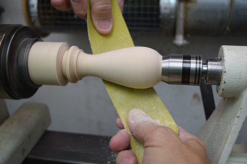 Passing sandpaper strip along toothpick holder blank